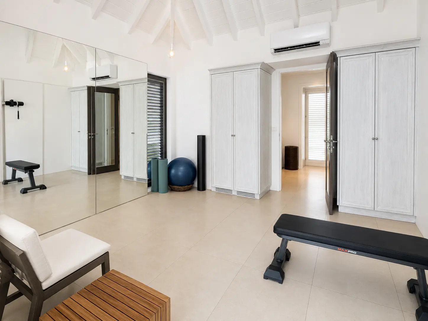 Private fitness room with mirrored wall, bench and yoga equipment