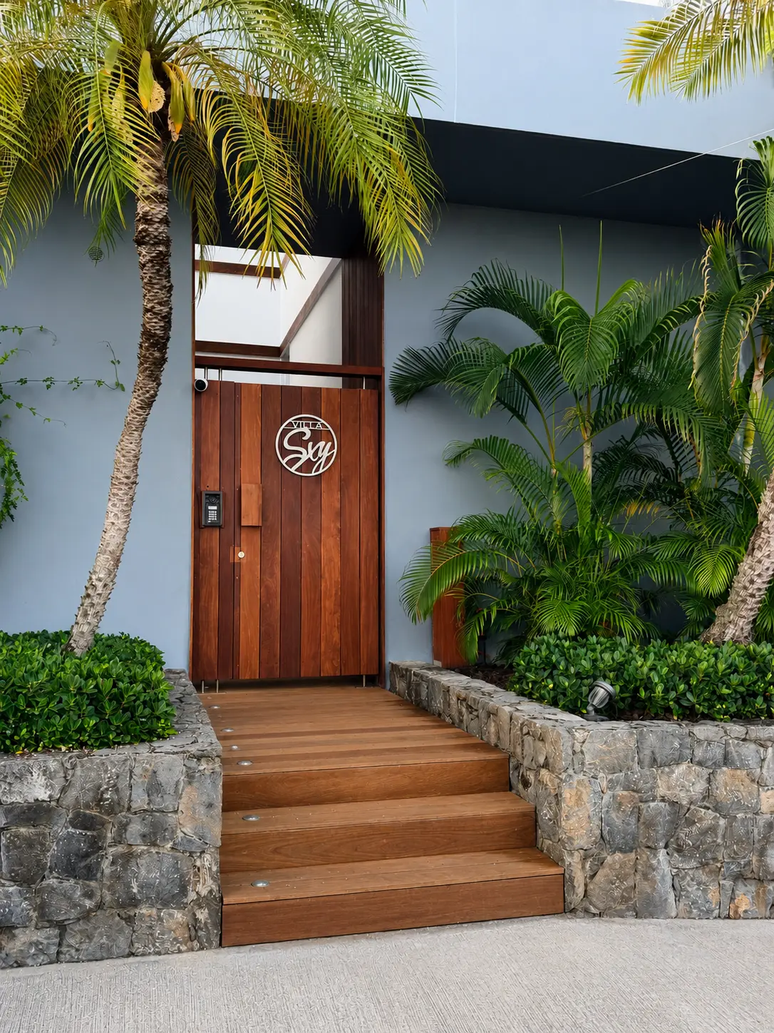 Timber entrance door of Villa SXY framed by palms