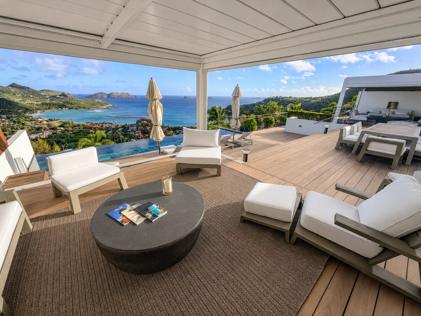 Wide terrace with the infinity pool and outdoor dining area above the ocean